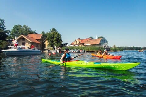Guided kayak tour in Vaxholm, Stockholm Archipelago — paddling past waterfront houses and island scenery.