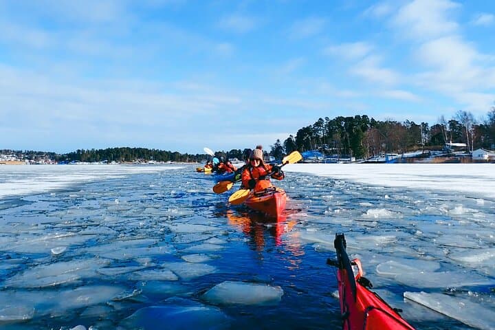 Kayakers paddling through icy waters of the Stockholm Archipelago during a winter adventure with Skärgårdens Kanotcenter