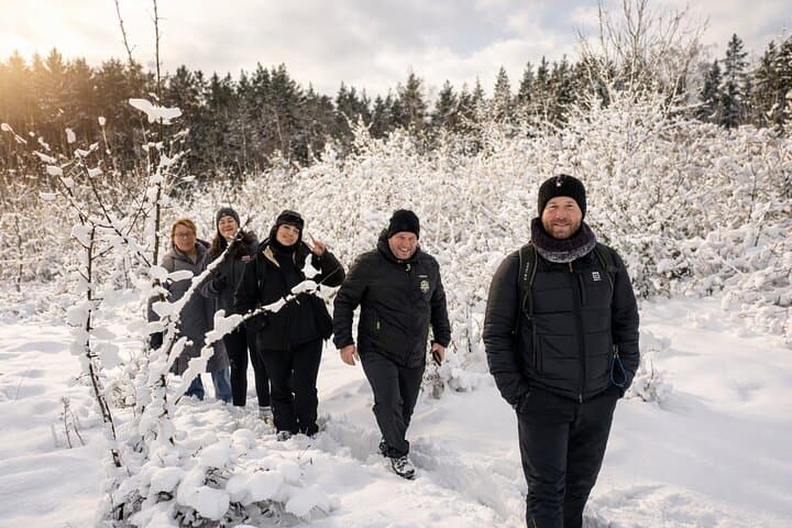 Winter hiking in the Stockholm Archipelago — a small group enjoying a snowy forest walk, surrounded by sunlit trees and fresh snow, sharing an easy, authentic moment outdoors.